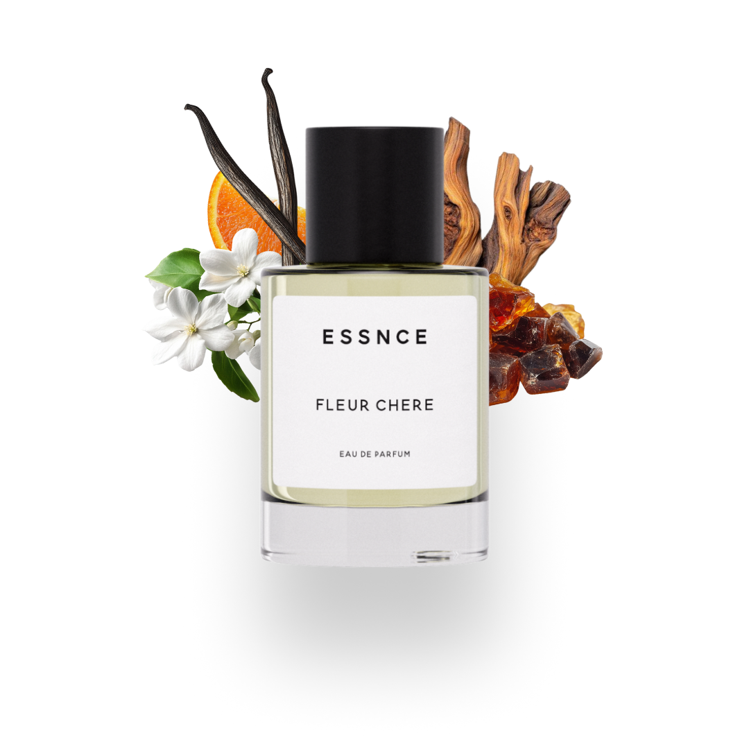 En flaska ESSNCE Fleur Chere Eau de Parfum visas med en svart kork och en vit etikett. Bakom flaskan finns ingredienser som apelsin, cederträ, jasmin, amber och vanilj.